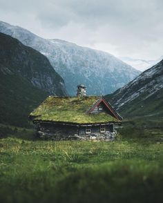 an old house with a green roof in the mountains