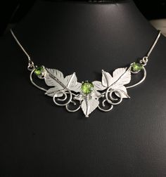 I've designed three sterling silver inspired leaves (with gentle vine work) which cradle an 8mm center gemstone of your choosing, with two side 6mm faceted Gems to offer symmetry and balance. This piece is approximately 1 and 1/4 inches in height and 2 and 1/4 inches across, but each may vary since I do make each one by hand - subtle variances will occur in the fabrication of the pendant. The pendant will come with an 18 inch, 1.2mm thick box chain, in sterling silver, with a lobster claw attach Leaf-shaped Sterling Silver Jewelry For Anniversary, Nature-inspired Leaf Shape Sterling Silver Jewelry, Silver Leaf-shaped Nature-inspired Jewelry, Silver Leaf Jewelry For Jewelry Making, Nature-inspired Sterling Silver Birthstone Jewelry, Silver Leaf-shaped Jewelry For Jewelry Making, Nature-inspired Silver Jewelry With May Birthstone, Nature-inspired Silver Jewelry With Emerald, Nature-inspired May Birthstone Jewelry