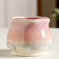 a pink and white vase sitting on top of a table