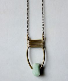 a gold necklace with a green stone hanging from it