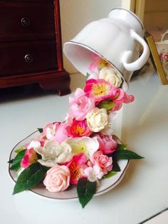 a white coffee cup with pink and white flowers in it sitting on a saucer