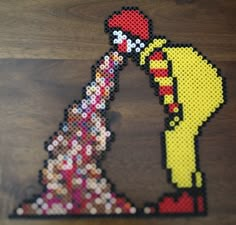 an image of a pixel art piece made out of legos and plastic beads on a wooden table