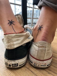 two small palm trees tattoo on the feet of people's legs, one is black and white