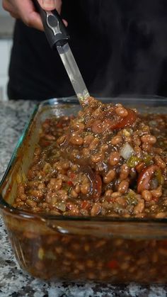 a person is cooking beans in a glass dish