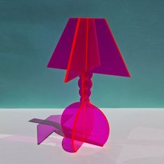 a purple lamp with a pink shade on it's side and a blue background