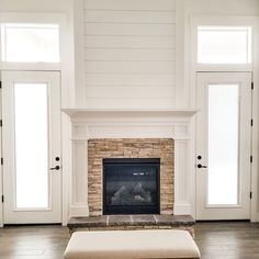 an empty living room with a fireplace and doors