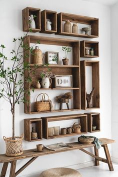 a wooden shelf with plants and baskets on it next to a bench in front of a wall