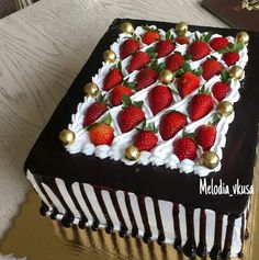 a chocolate cake with white frosting and strawberries on top is sitting on a table