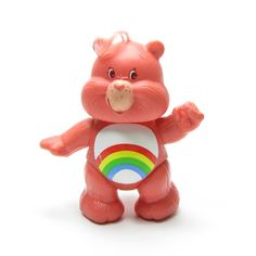 a toy bear holding a rainbow ball on a white surface with one hand up and the other in the air