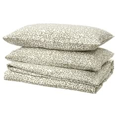 three pillows stacked on top of each other in front of a white background with green leaves