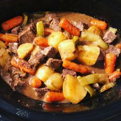 a crock pot filled with stew and carrots