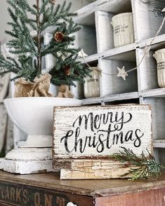 a wooden sign sitting on top of a table next to a christmas tree and other decorations