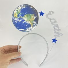 a hand holding a headband that has the earth on it and stars around it