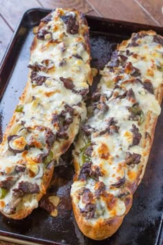 two pieces of bread sitting on top of a baking pan covered in cheese and toppings