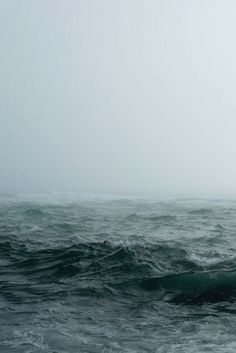 a person riding a surfboard on top of a wave in the ocean with fog