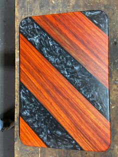 a wooden cutting board sitting on top of a metal table next to a blue and black object