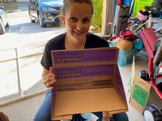 a woman sitting on the ground holding up a box