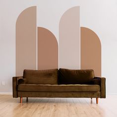 a brown couch sitting in front of a wall with arches painted on it's sides