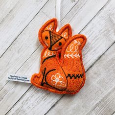 an orange cat ornament hanging on a white wooden wall