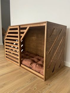 a dog house made out of wood with a bed in the middle and pillows inside