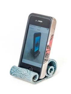 a cell phone sitting on top of a holder with two rolled up papers in front of it