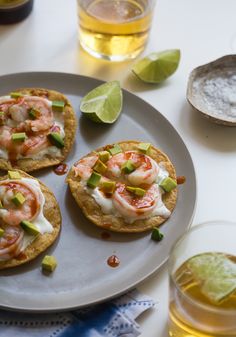 small appetizers with shrimp and avocado are on a plate next to glasses of beer