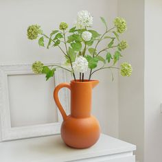 an orange vase with white flowers in it