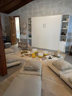 a living room filled with lots of furniture and pillows on top of carpeted floor