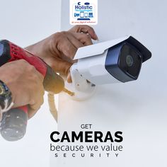 a man holding a video camera next to a white wall with the words get cameras because we value security