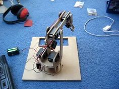 a robot sitting on top of a piece of wood next to a remote control system