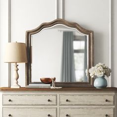 a dresser with a mirror, lamp and vase on it