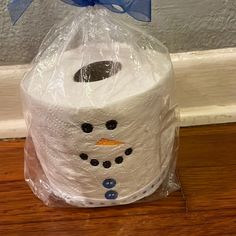 a toilet paper roll wrapped in plastic with a snowman face on it and a blue bow