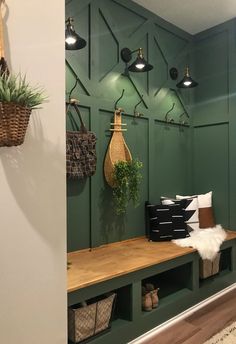 a room with green painted walls and wooden shelves filled with baskets, hanging planters and other decorative items