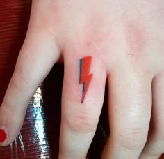 a person's hand with a red and blue lightning bolt tattoo on the middle finger