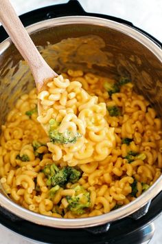 a wooden spoon in a pot filled with macaroni and cheese