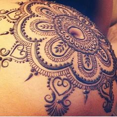 the back of a woman's stomach with henna tattoos on it and an intricate design