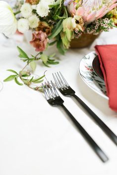 the table is set with silverware and flowers