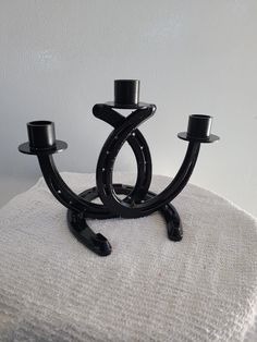 two black candlesticks sitting on top of a white cloth