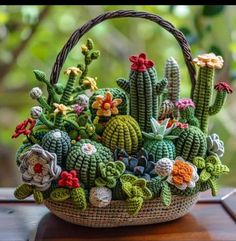 a basket filled with crocheted cacti sitting on top of a wooden table