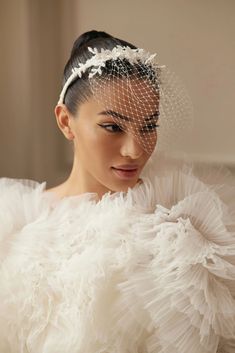 a woman in a white dress with a birdcage on her head and veil