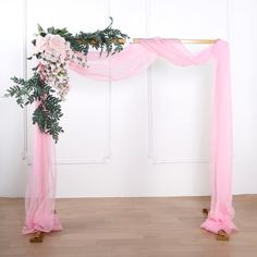 a pink and white wedding arch decorated with flowers