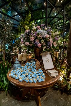 a table topped with lots of blue and white cookies next to a vase filled with flowers