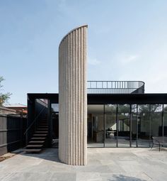 a tall column sitting in the middle of a patio next to a building with glass doors