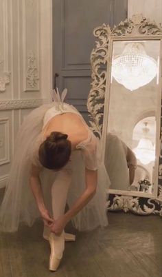 a ballerina is bending over in front of a mirror