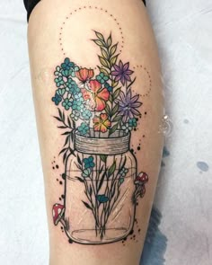 a woman's leg with flowers in a jar tattoo on it