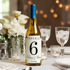 a bottle of wine sitting on top of a table next to glasses and flowers in vases