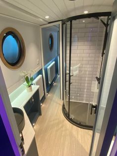 a bathroom with a walk in shower sitting next to a sink and toilet on top of a hard wood floor