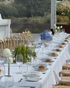 a long table is set up with white linens and blue flowers in vases