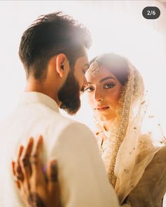 a bride and groom standing close together in front of the sun shining through the window