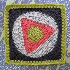 a crocheted square with a red, white and green design on it's center